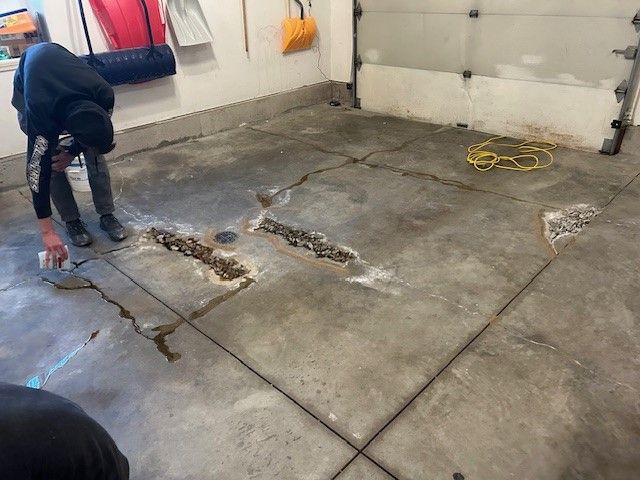 A person is cleaning a concrete floor in a garage.