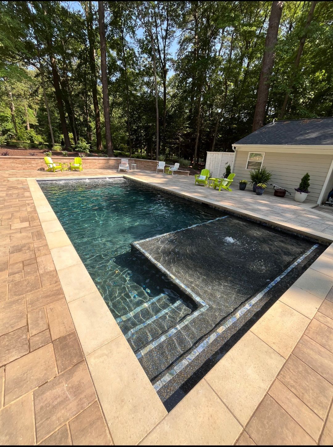 A large swimming pool with stairs leading to it is surrounded by trees.