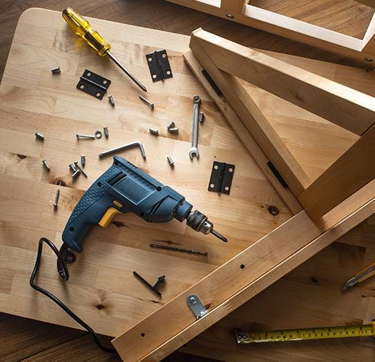 a drill is sitting on top of a wooden table surrounded by tools .