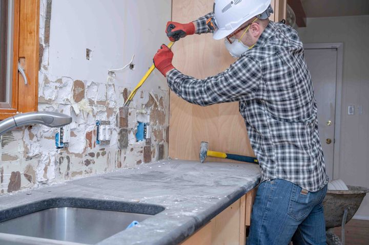 a man wearing a hard hat is working on a kitchen counter