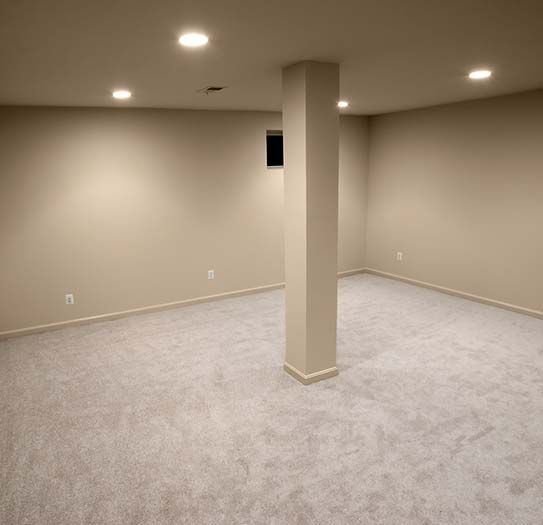 an empty basement with a pillar in the middle of the room .