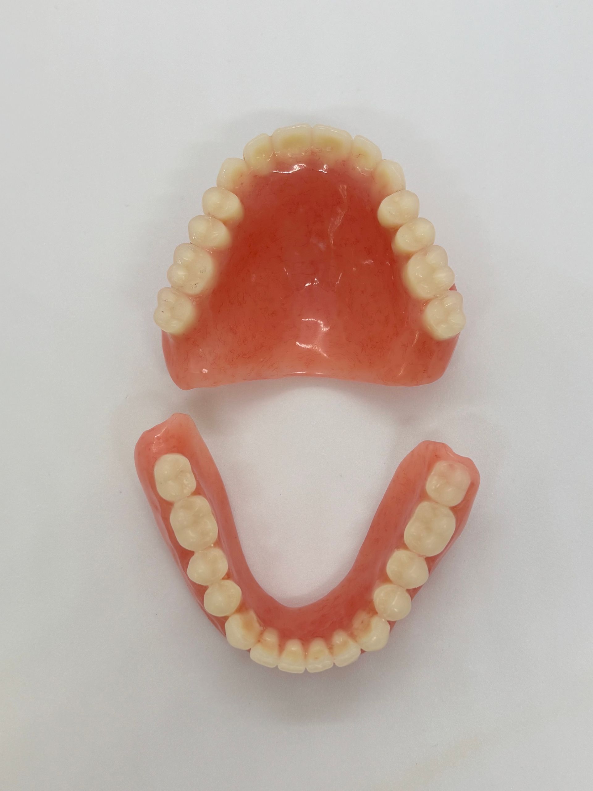 Set of Upper and Lower Pink Dentures on a White Background — Precise Dentures in Berserker, QLD