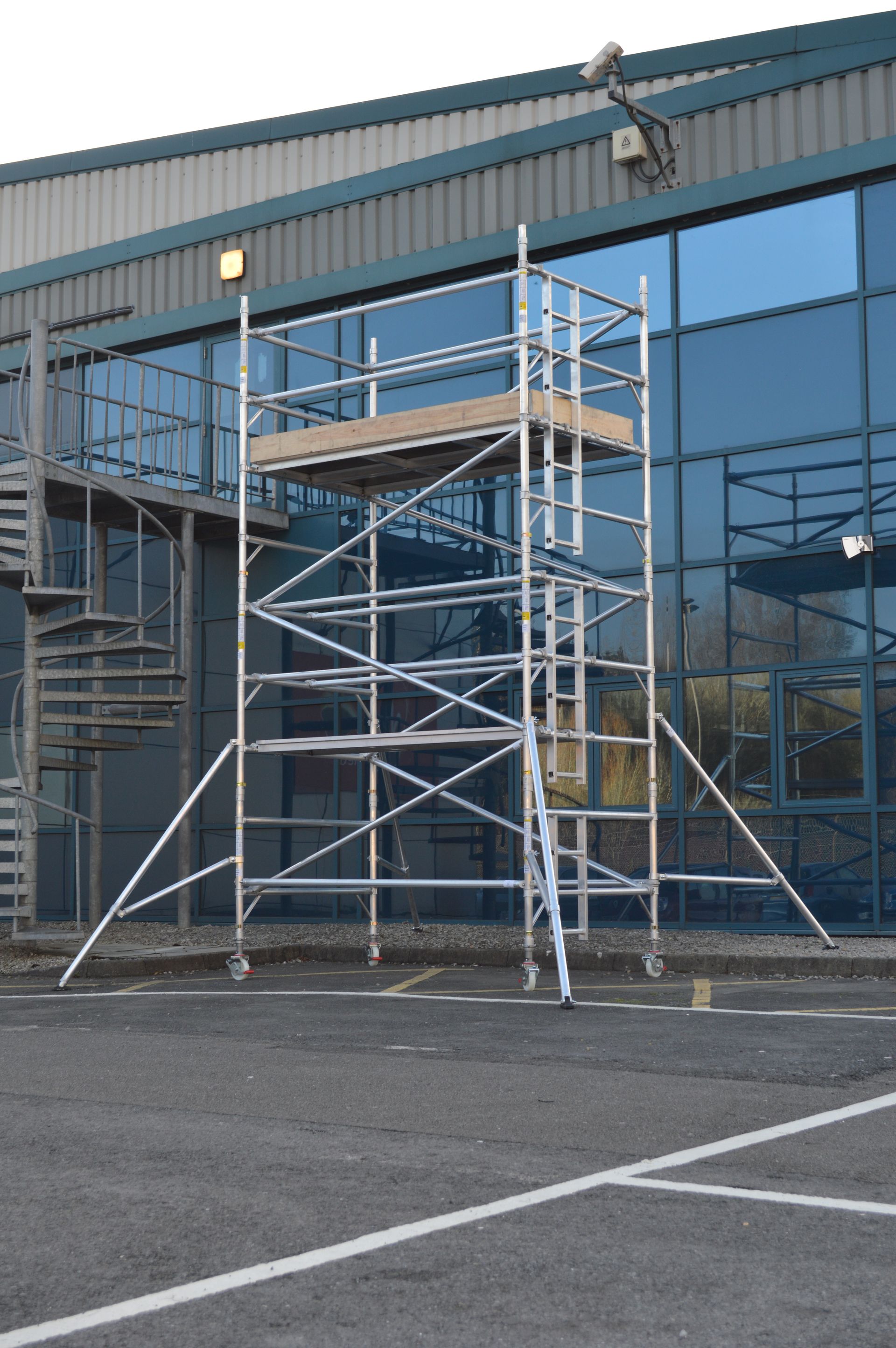 A scaffolding is sitting in front of a building in a parking lot.