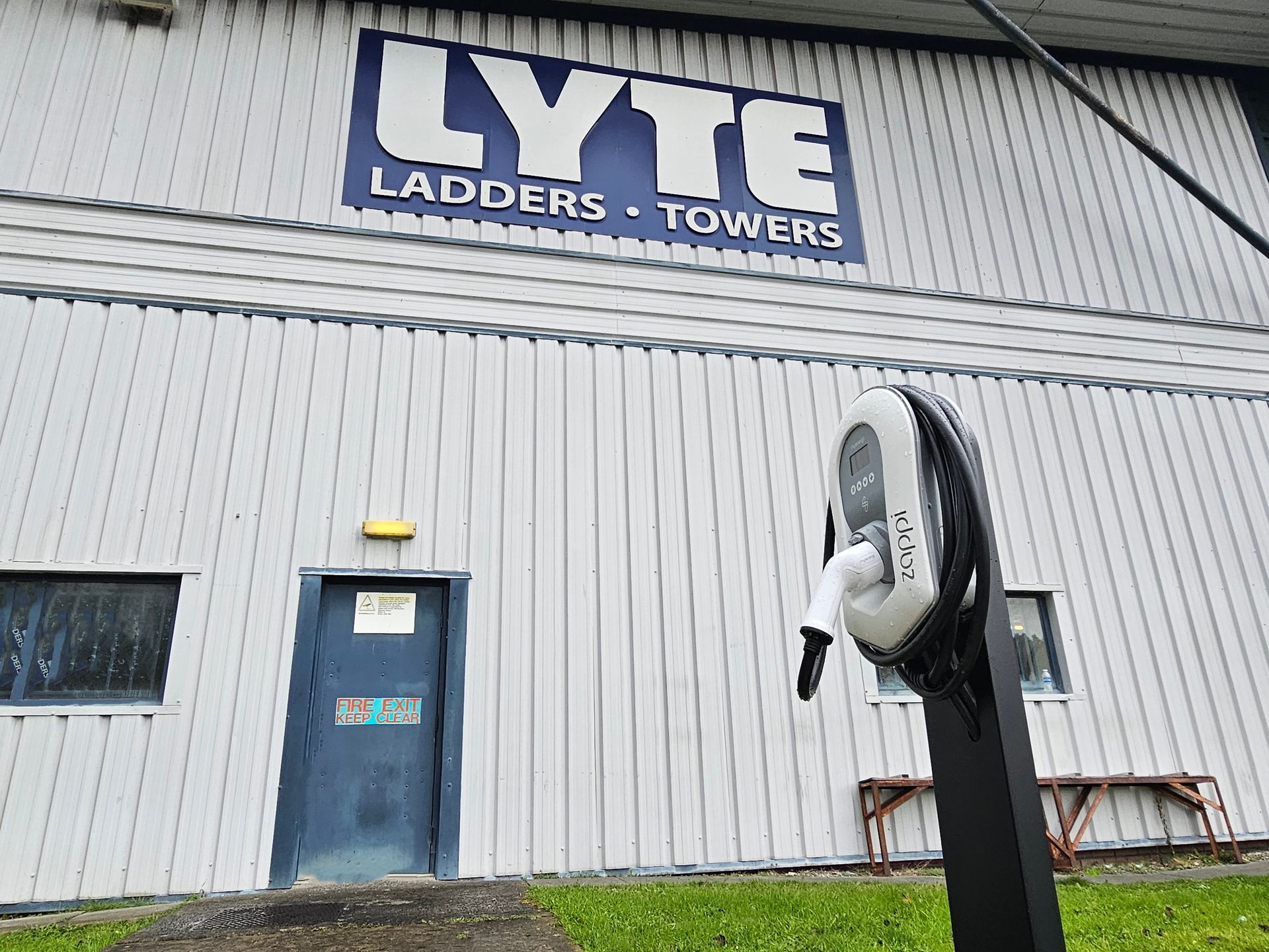 A lyte ladder and towers building with a charging station in front of it.