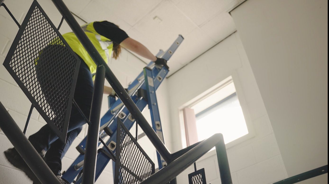 Maintenance worker climbing the Lyte Professional Combination Ladder in an stairwell