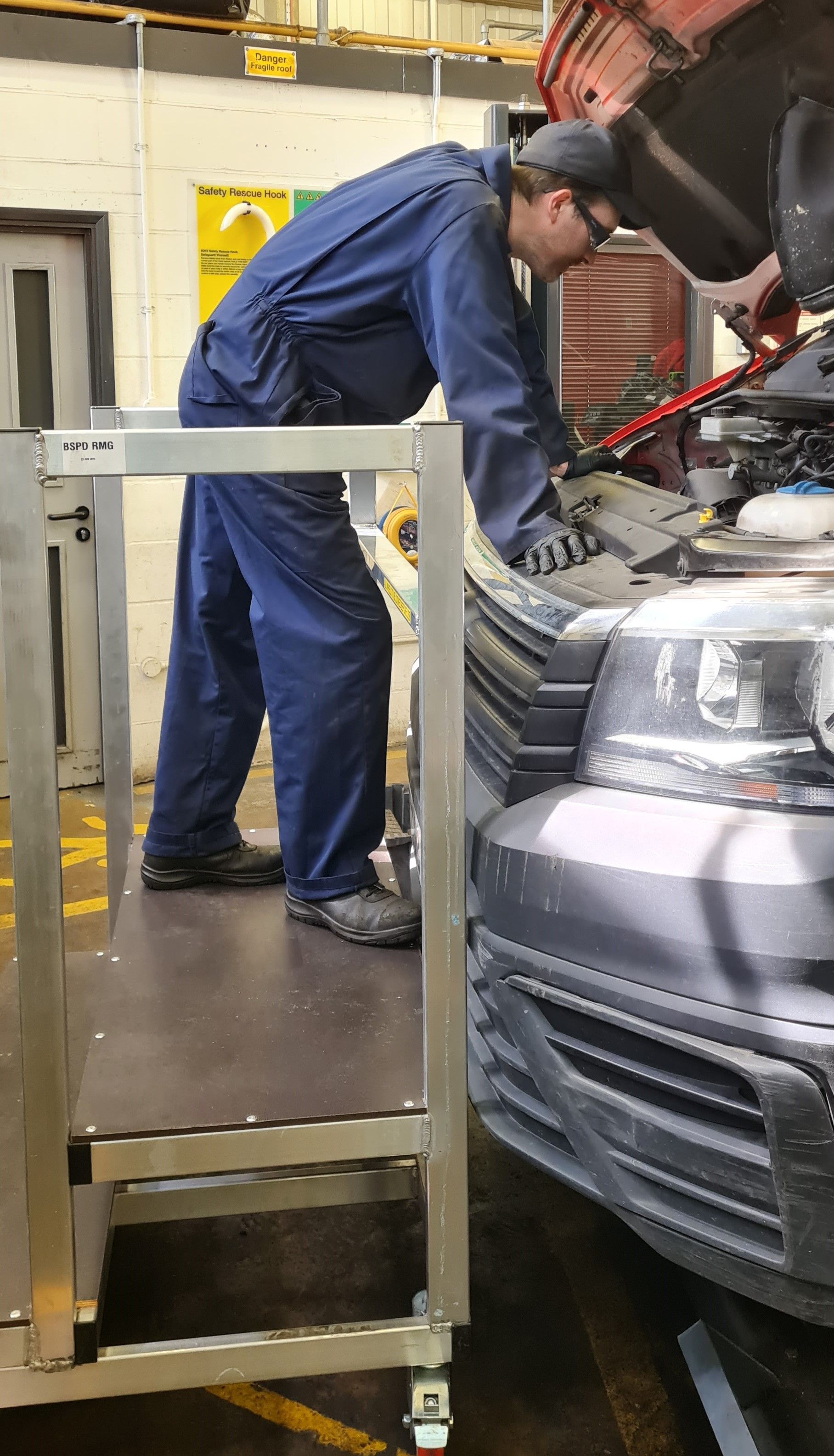 A man is working on the engine of a car in a garage.