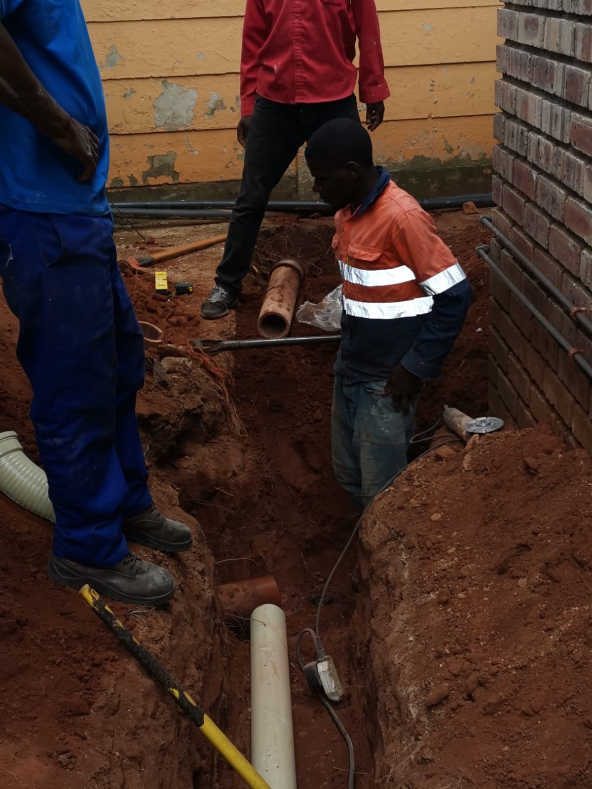 Plumbers installing underground pvc plumbing pipes