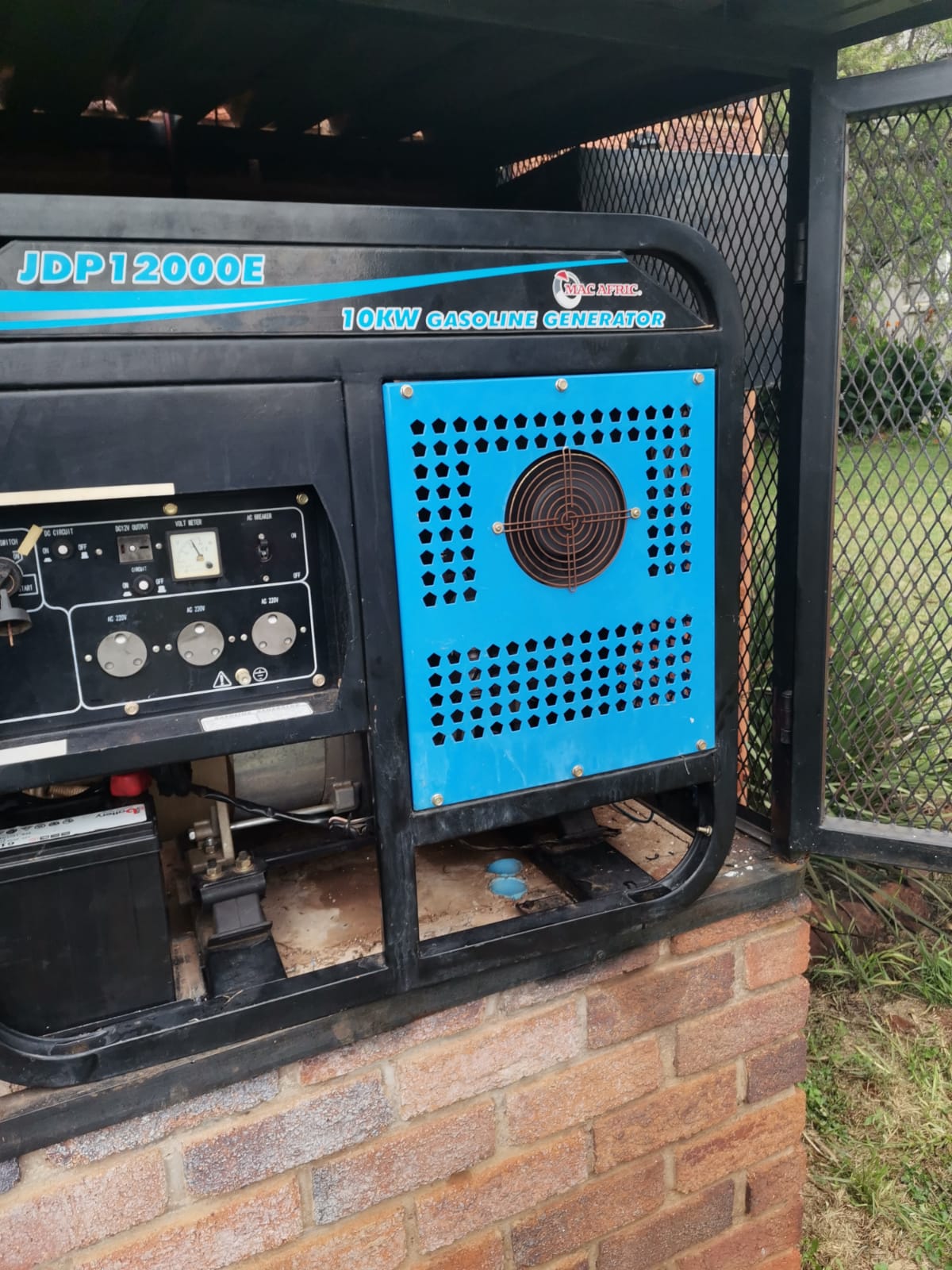 Fuel generator installed on a cement and brick block with a protective cage around it