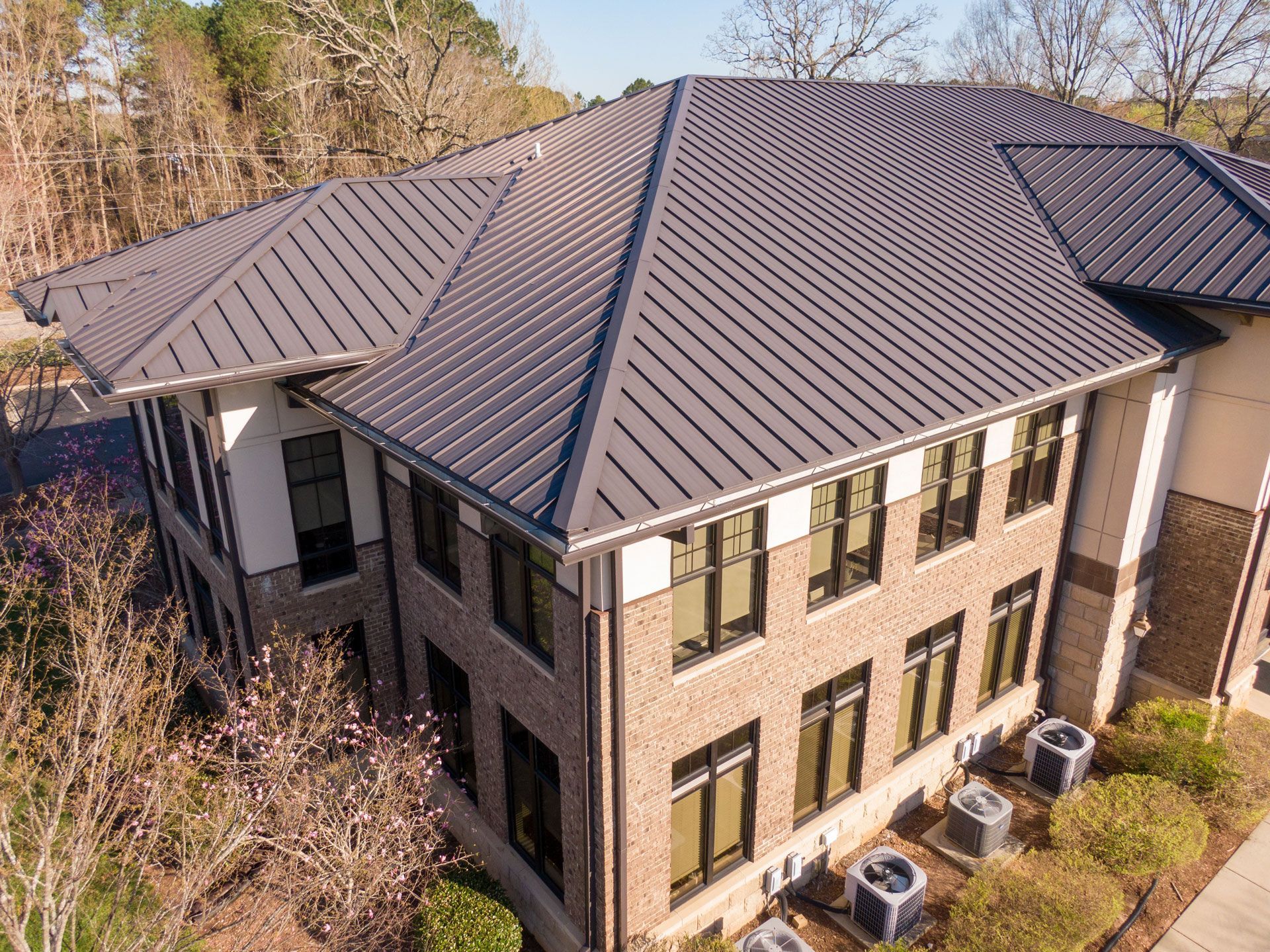 Two-story brick building with a dark metal roof and multiple windows.