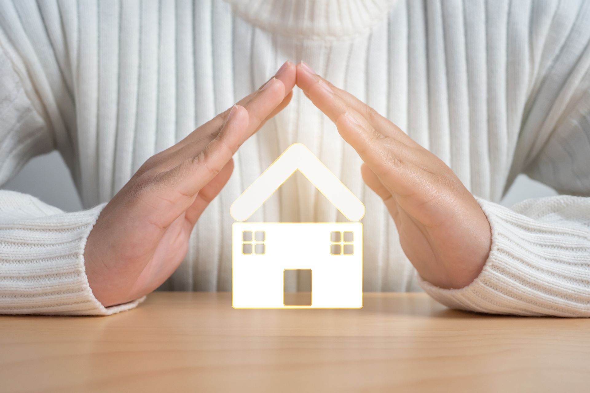 Hands cupped over a glowing house cutout, symbolizing protection or home ownership.