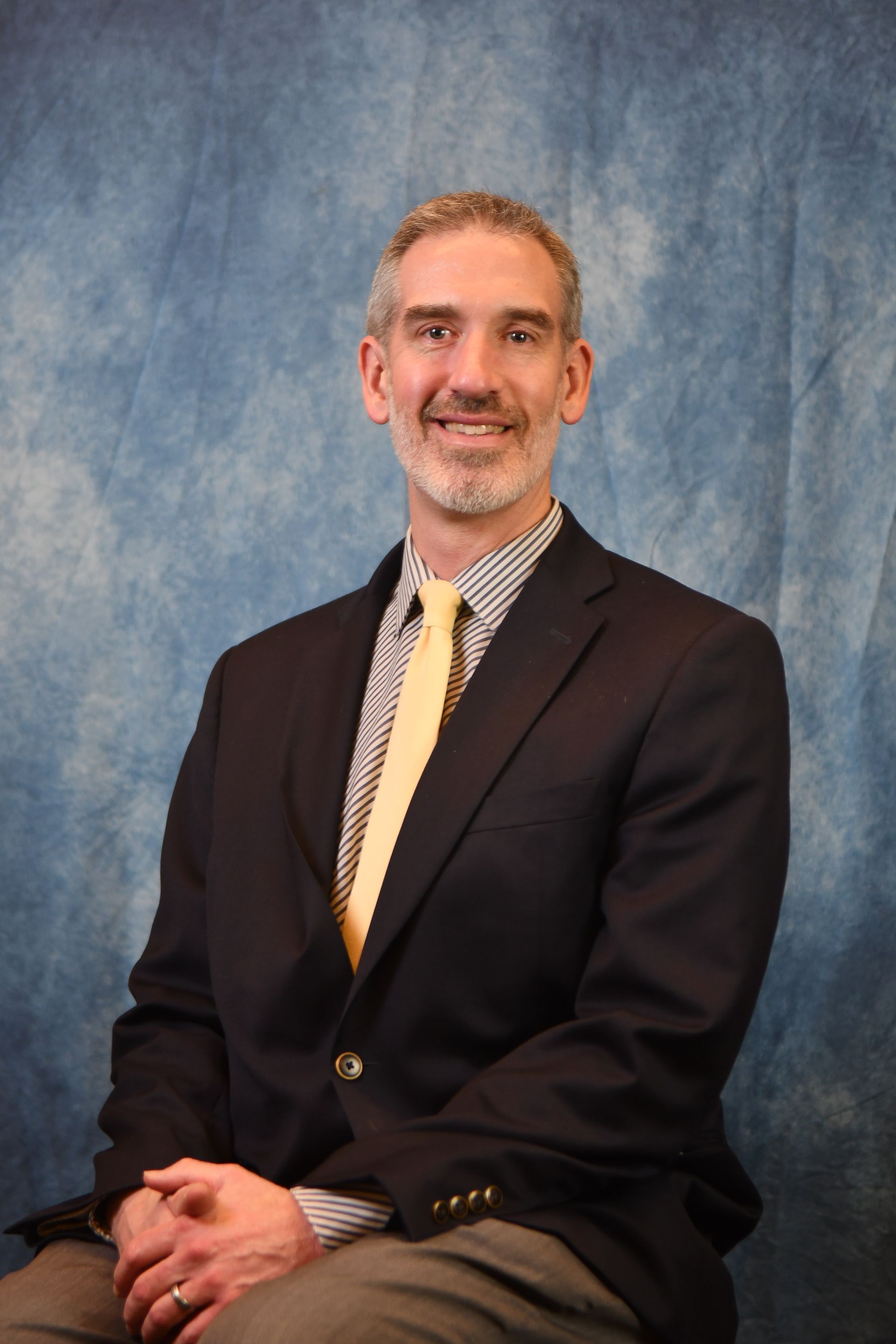 A man in a suit and tie is smiling for the camera.