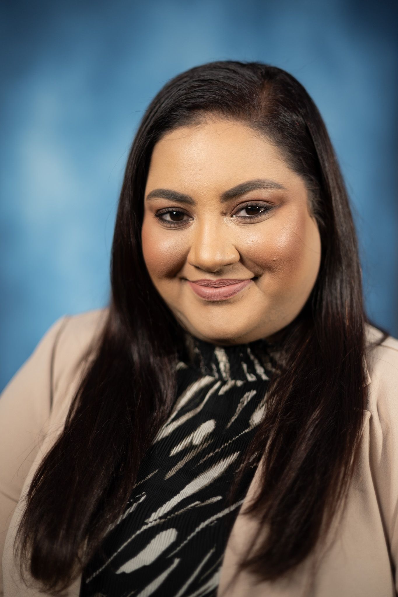 A woman in a blue jacket and black shirt is smiling for the camera.