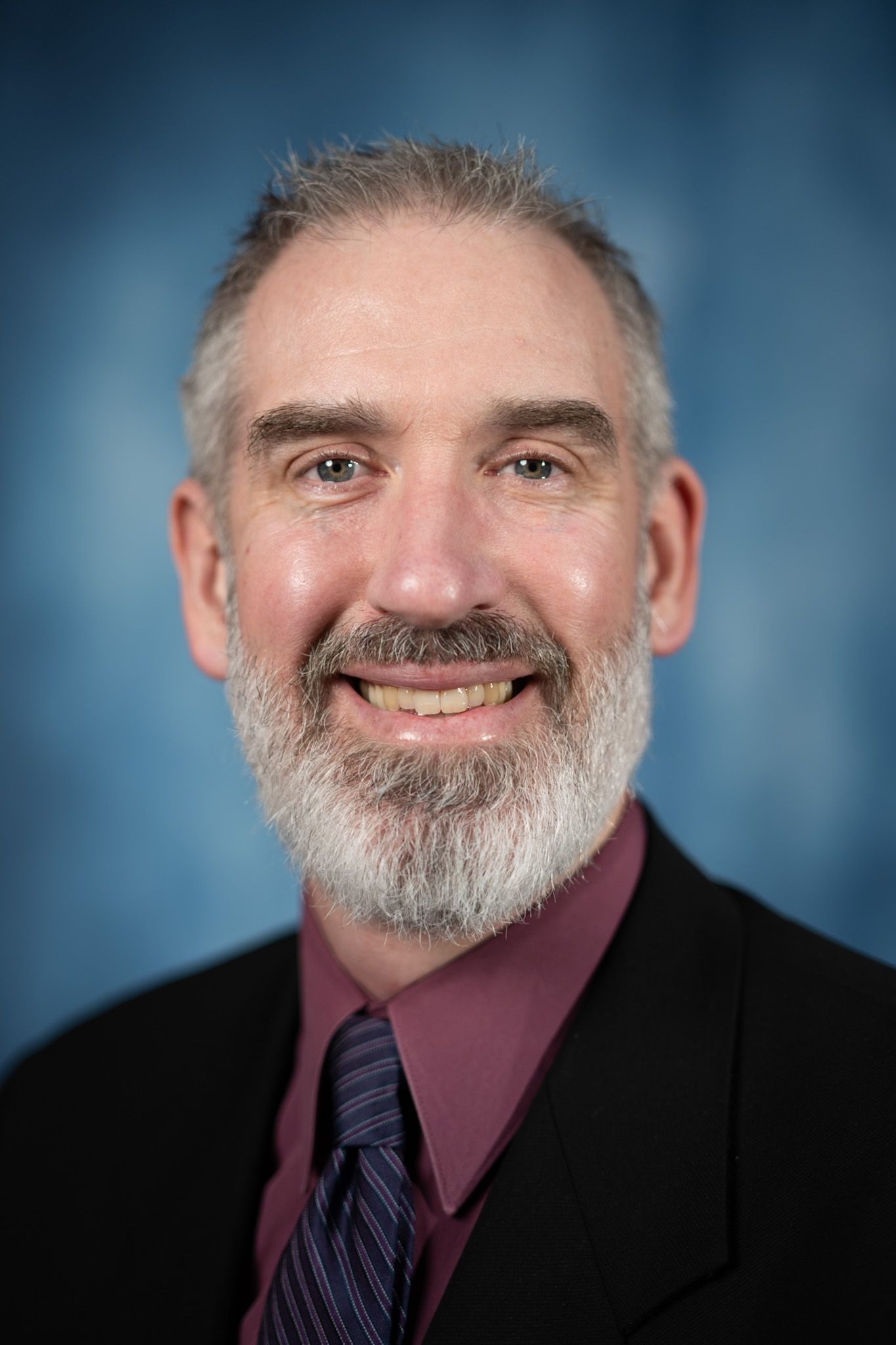 A man in a suit and tie is smiling for the camera.