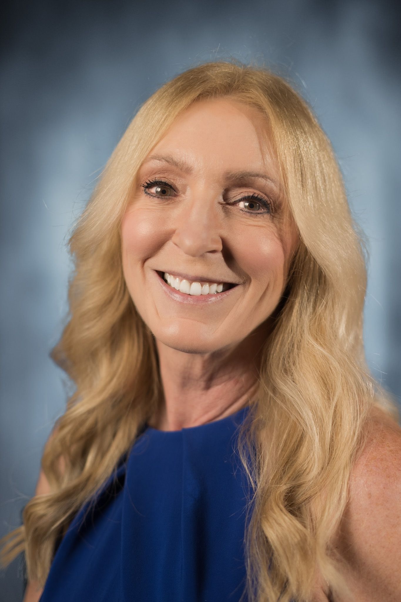 A woman wearing a red shirt and a necklace is smiling for the camera.