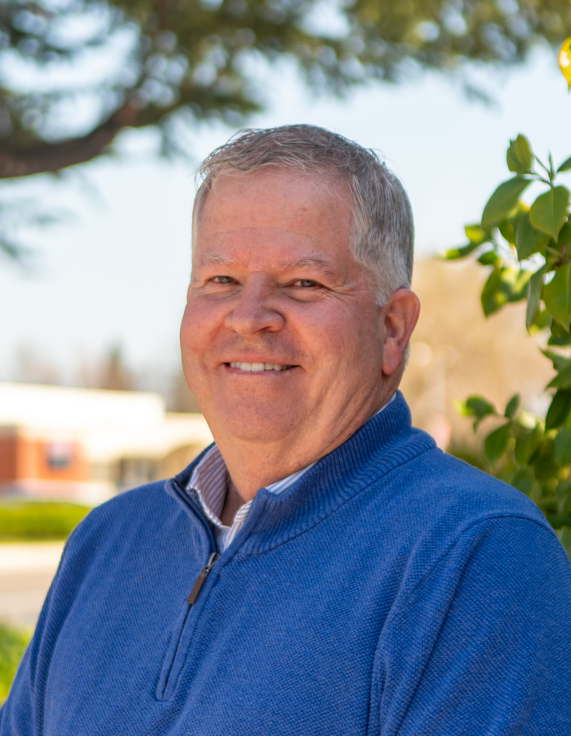 A man in a blue shirt is smiling for the camera.