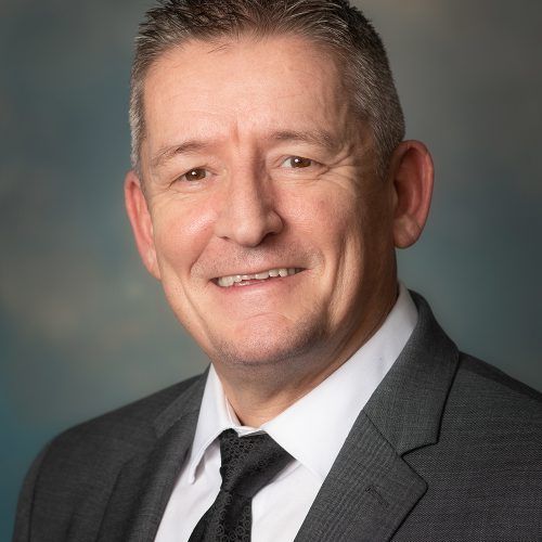 A man in a suit and tie is smiling for the camera.