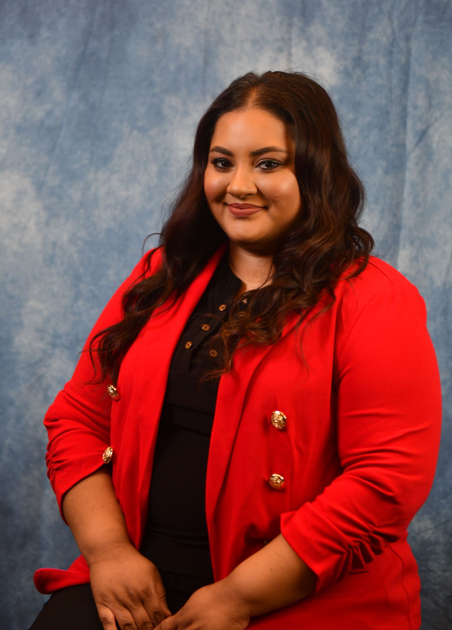 A woman in a blue jacket and black shirt is smiling for the camera.
