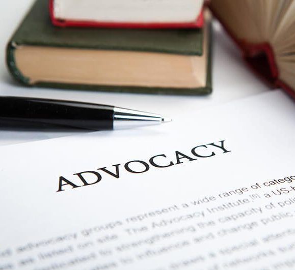 A pen is on a piece of paper that says advocacy