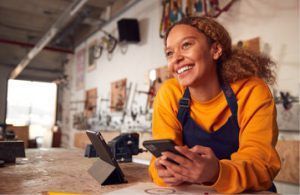 A woman is sitting at a table using a cell phone.