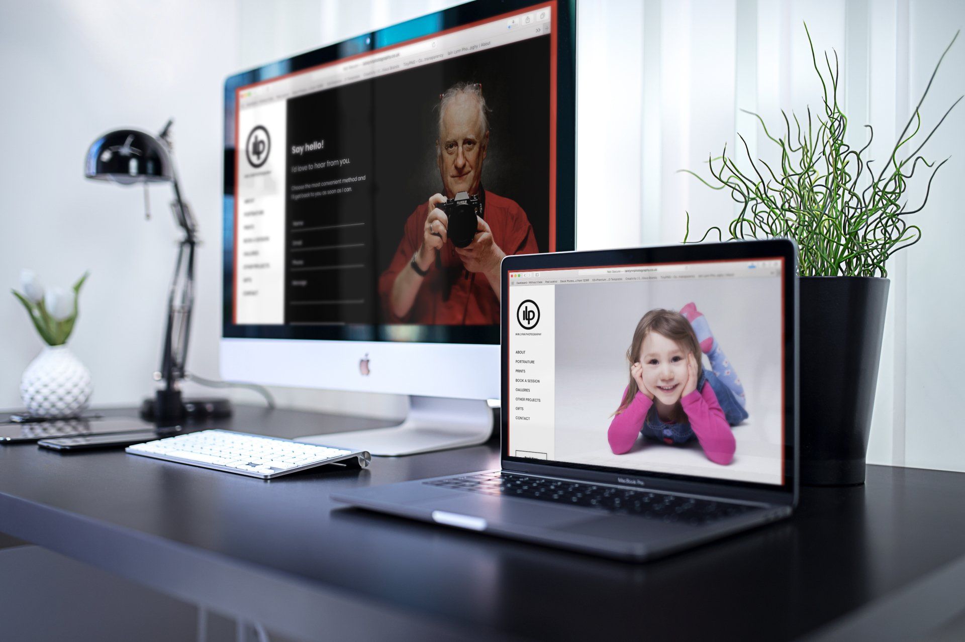 Desktop setup with computer screens displaying a photographer's website featuring photos of a woman and a child.