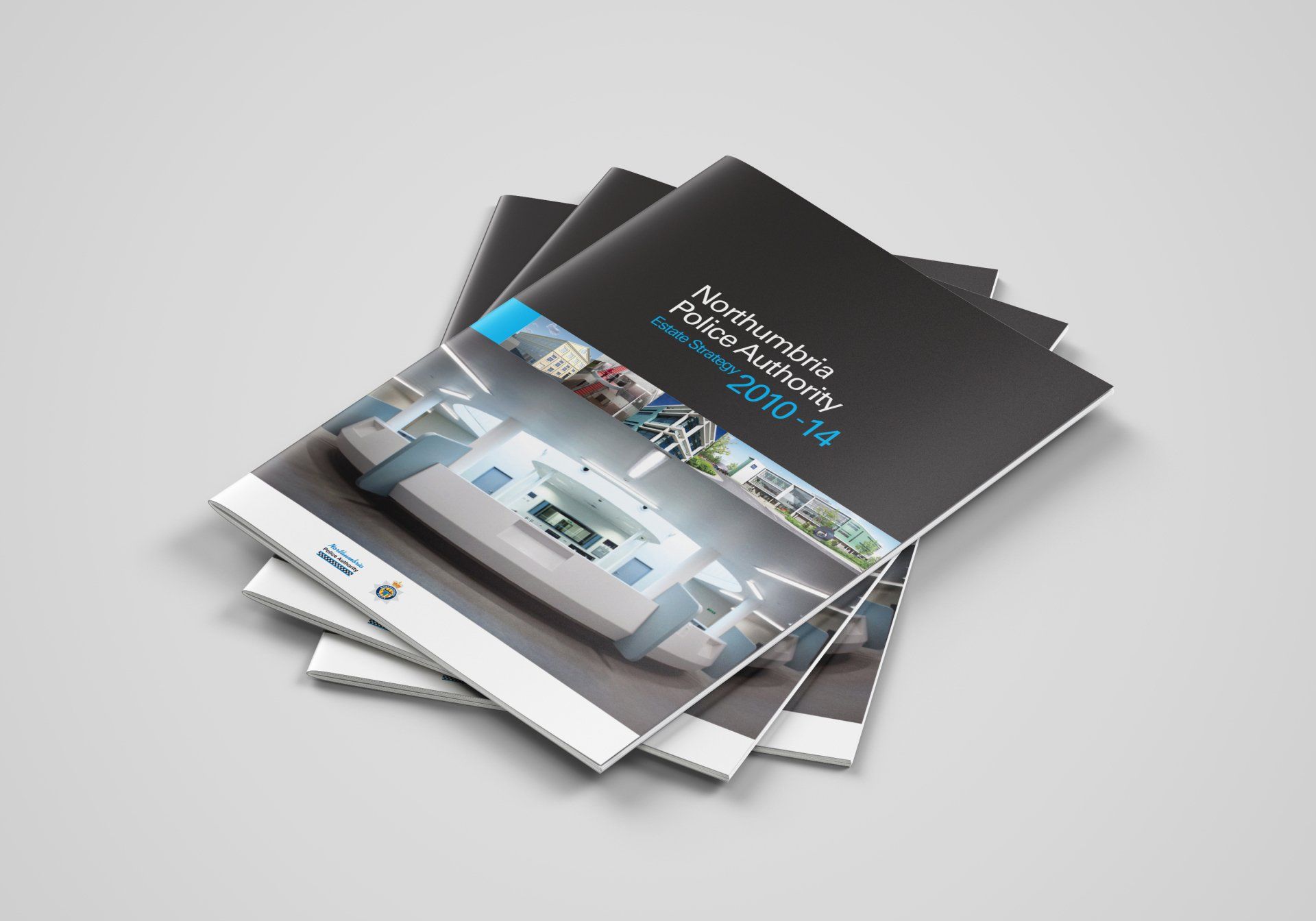 Brochures stacked on a surface, the top brochure has a black cover and a photo of a modern interior.