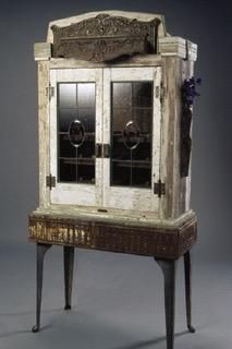 A wooden cabinet with stained glass doors is sitting on top of a wooden table.