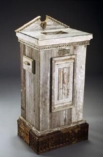 A wooden box is sitting on top of a wooden pedestal on a table.