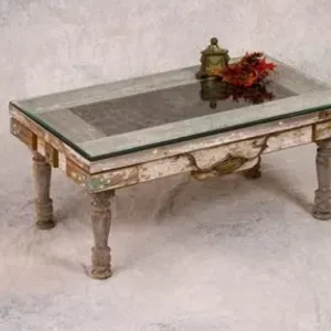 A coffee table with a glass top and flowers on it.