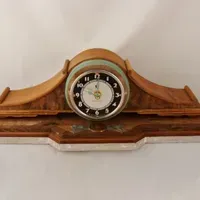 A wooden mantle clock with a clock on top of it.