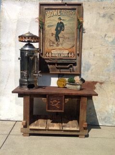 A wooden table with a coffee maker and a painting on it.