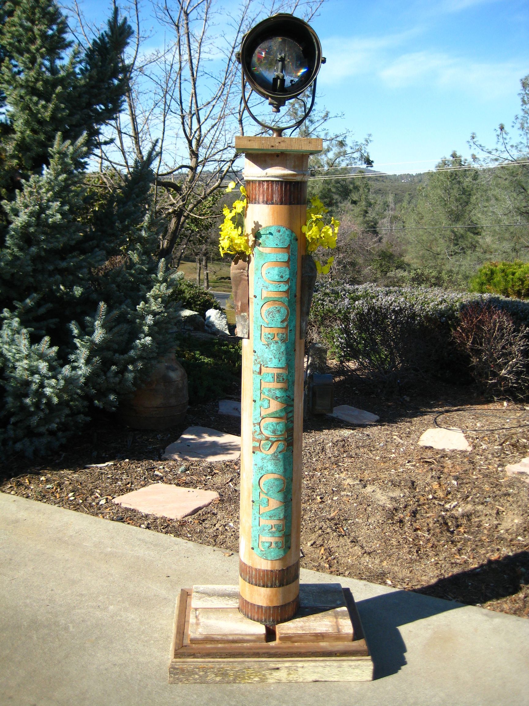 A wooden pole with flowers on top of it in a garden.