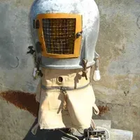 A statue of a robot with a helmet on it is sitting on a concrete surface.
