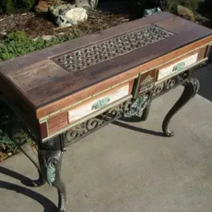 A wooden table with drawers and a metal frame is sitting on a sidewalk.