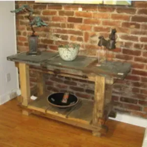 A wooden table with a bowl on it in front of a brick wall