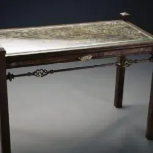 A wooden table with a glass top is sitting on a gray floor.