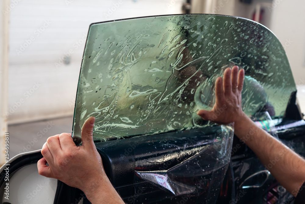 Image of a person applying tint to a car window.