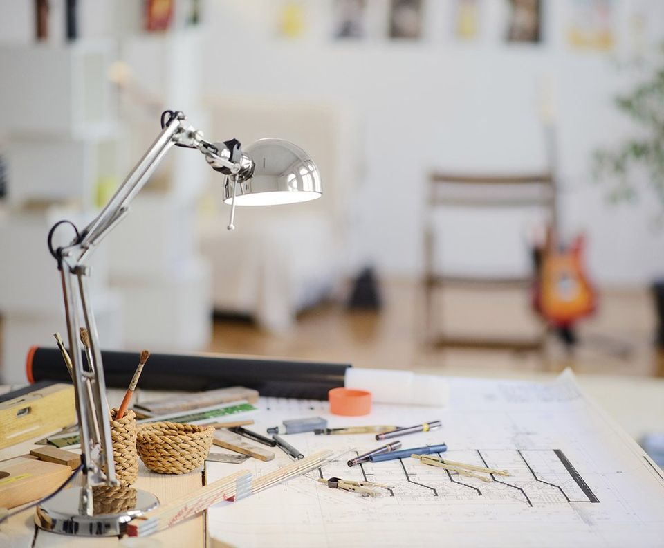 an architects drawing desk with lamp pens and pencils