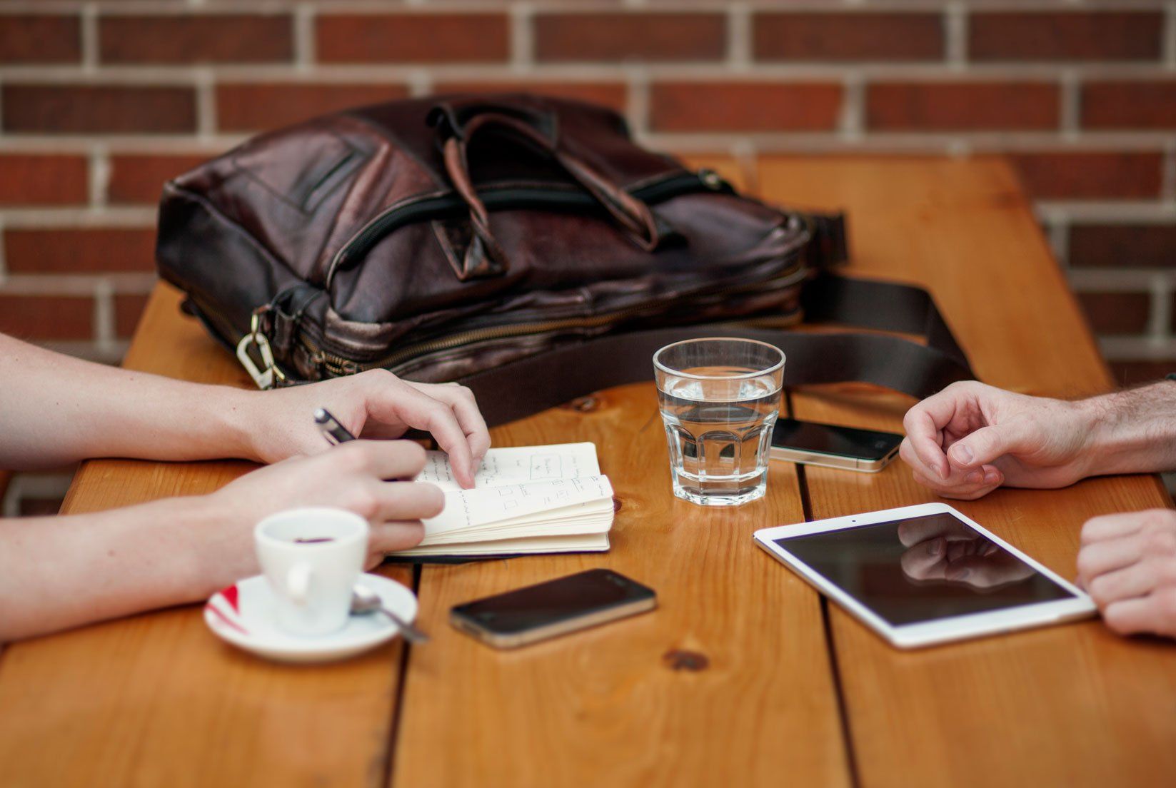 A group of people are sitting at a table with a tablet and a cup of coffee.