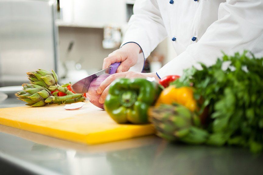 a chef is cutting vegetables on a cutting board in a kitchen.