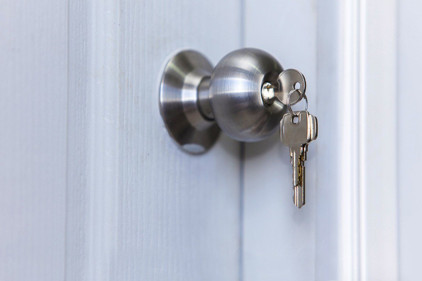 chrome doorknob with key inserted and a secondary key hanging off of the key that's inserted