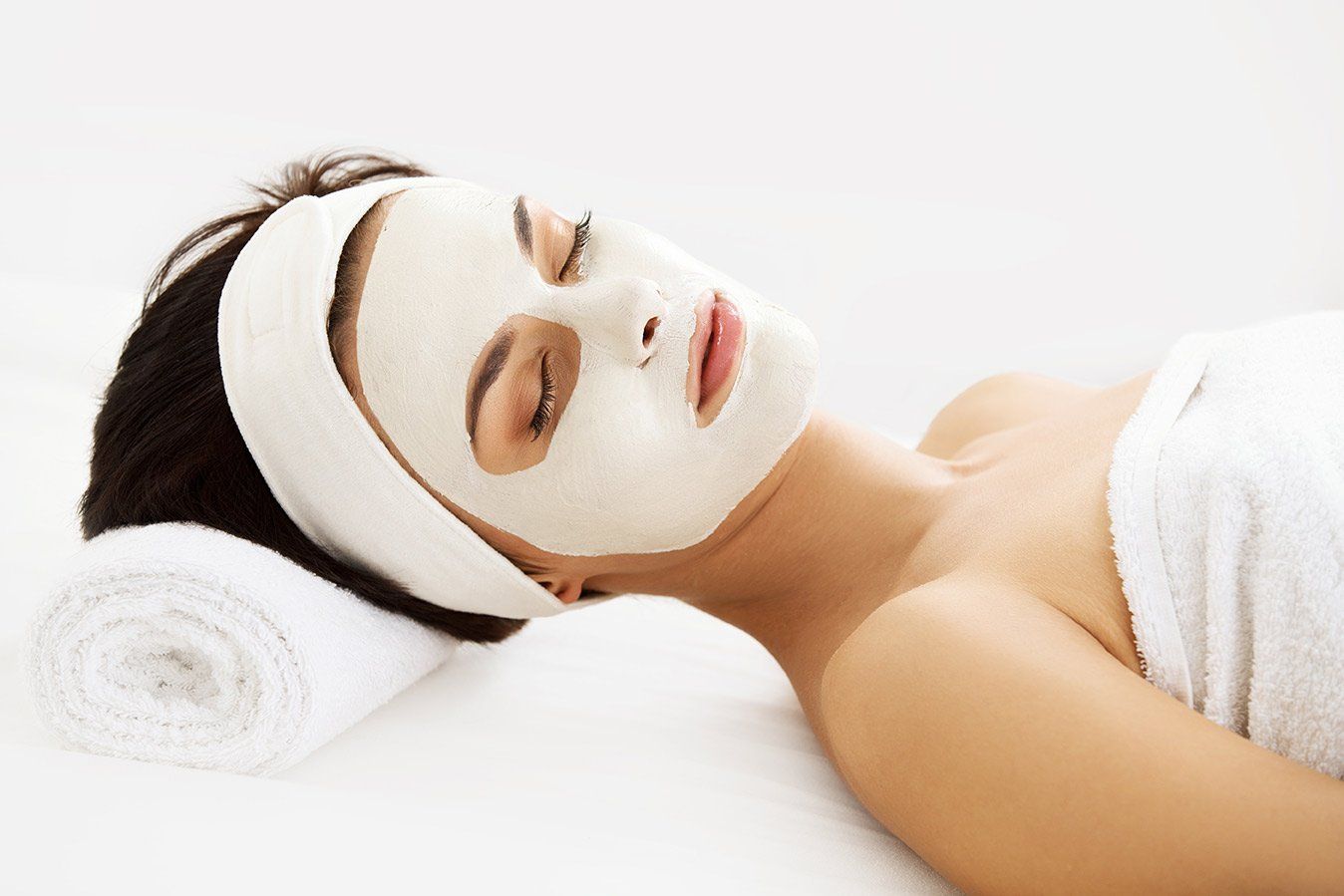 Lady with a white headband having a facial. With a white facial mask.