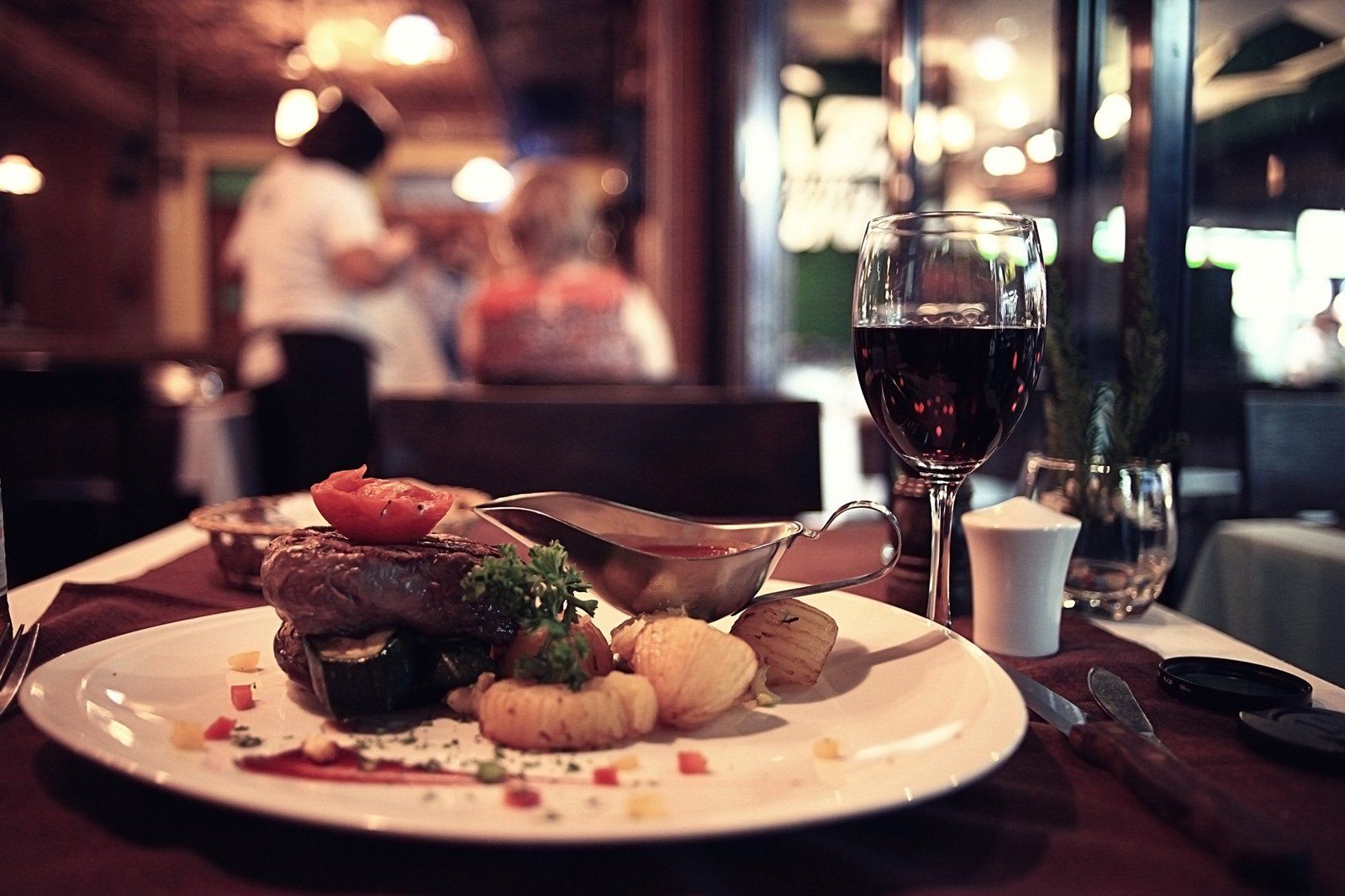 A plate of food and a glass of wine on a table in a restaurant.