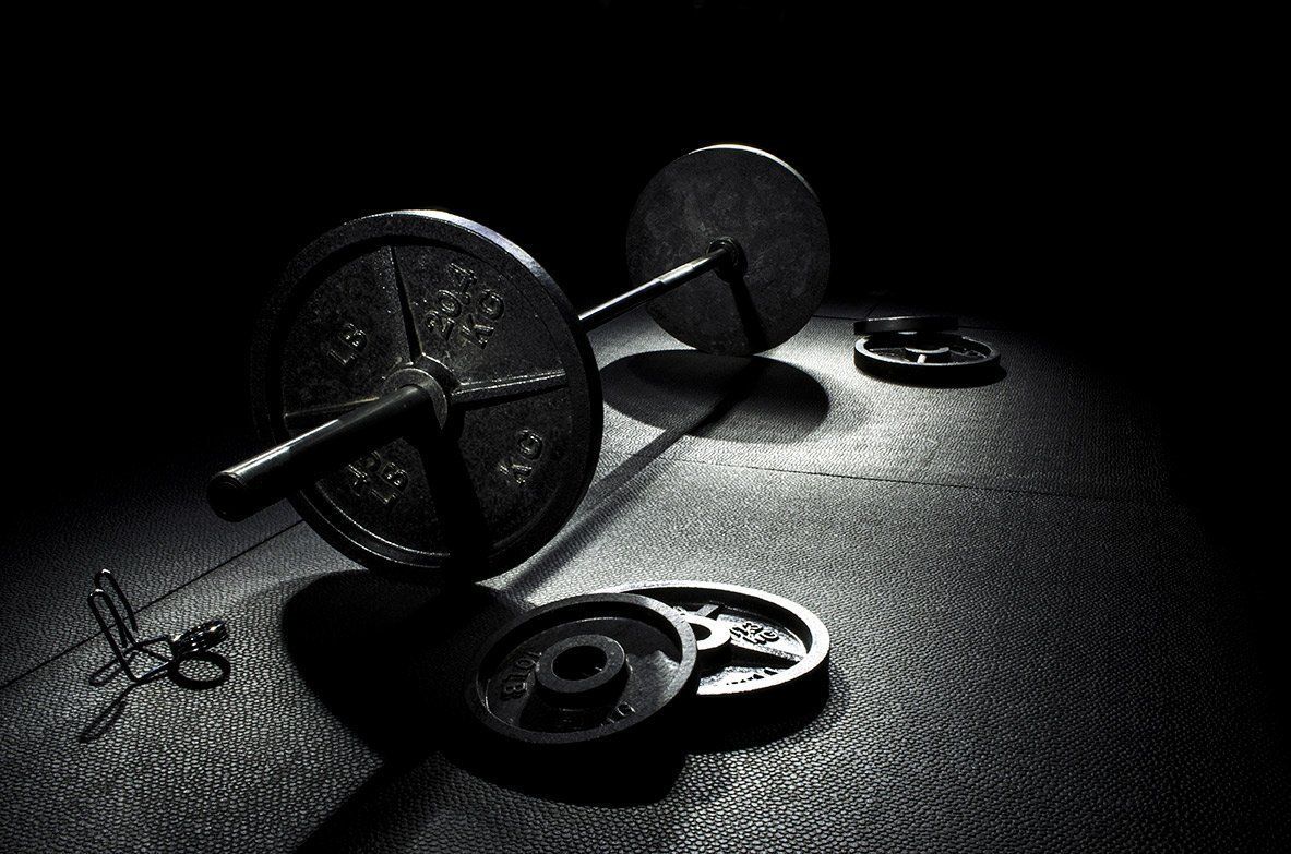 a black and white photo of a barbell and weight plates on the floor 