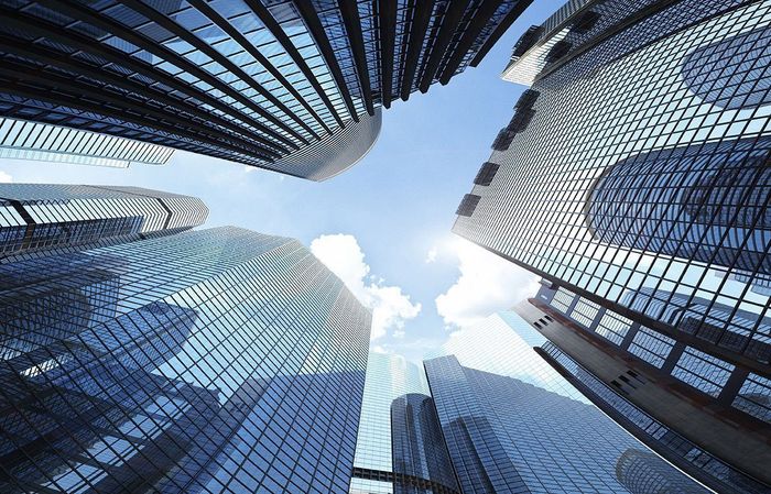 Looking up at a group of skyscrapers against a blue sky.