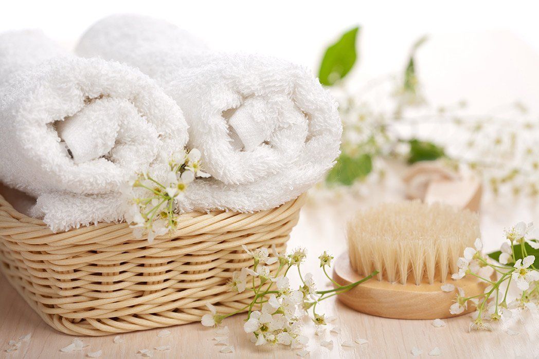 A wicker basket filled with white towels and a wooden brush.