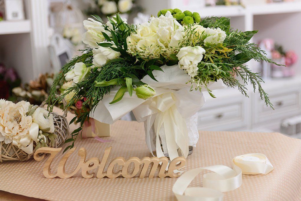 a vase filled with white flowers is sitting on a table next to a welcome sign .