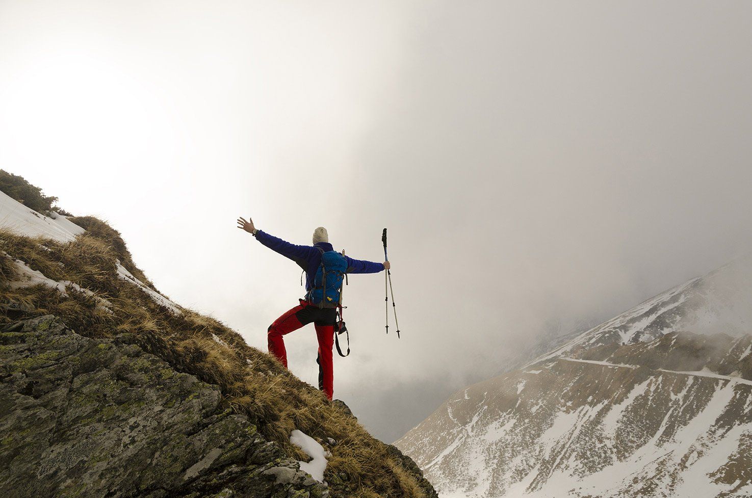 a man is standing on top of a snowy mountain with his arms outstretched .