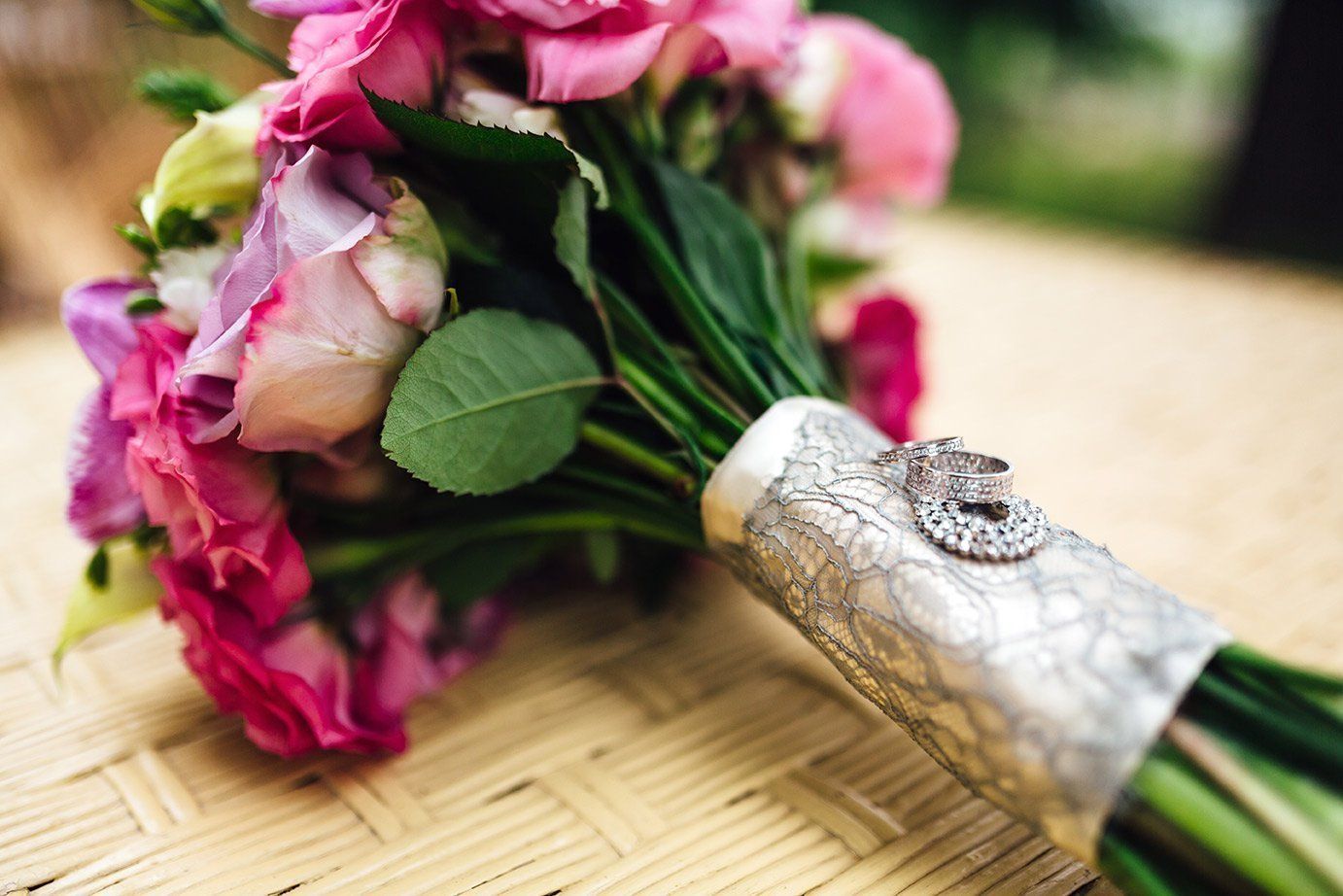 a bouquet of pink flowers sits next to a silver ring
