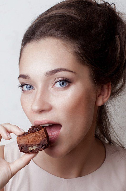 una donna con gli occhi azzurri mangia un pezzo di torta al cioccolato