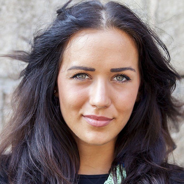 a close up of a woman 's face with dark hair and green eyes